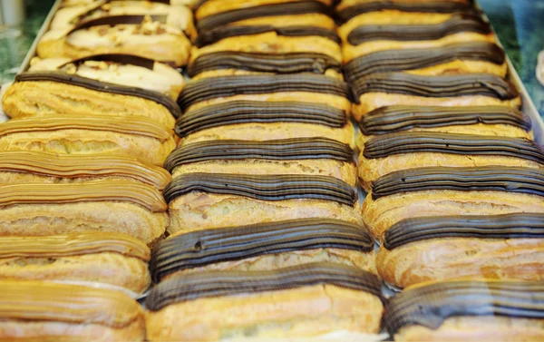 Tasty eclairs on in french bakery store — Stock Photo, Image