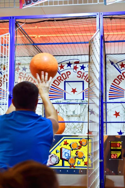 Man playing basketball in amusement park at dusk — Stock Photo, Image