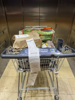 Karlsruhe, Almanya - 30 Eylül 2025: Kese kağıdı, yeniden kullanılabilir alışveriş torbaları ve gidona asılı uzun makbuzlu satın alınan eşyalar.