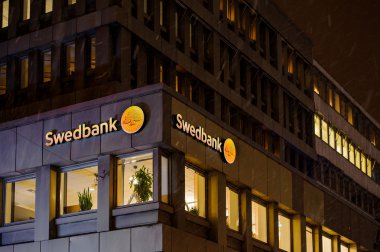 Swedbank logo on a snowy night on the building facade clipart