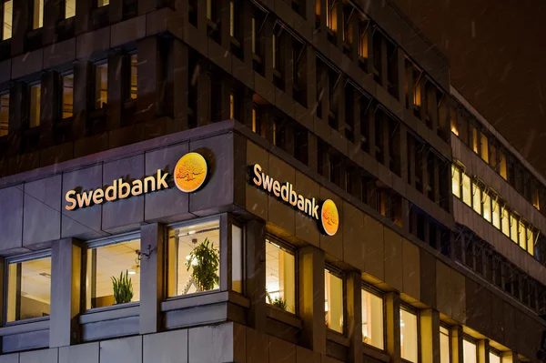 Swedbank λογότυπο σε μια χιονισμένη νύχτα στην πρόσοψη του κτιρίου — Φωτογραφία Αρχείου