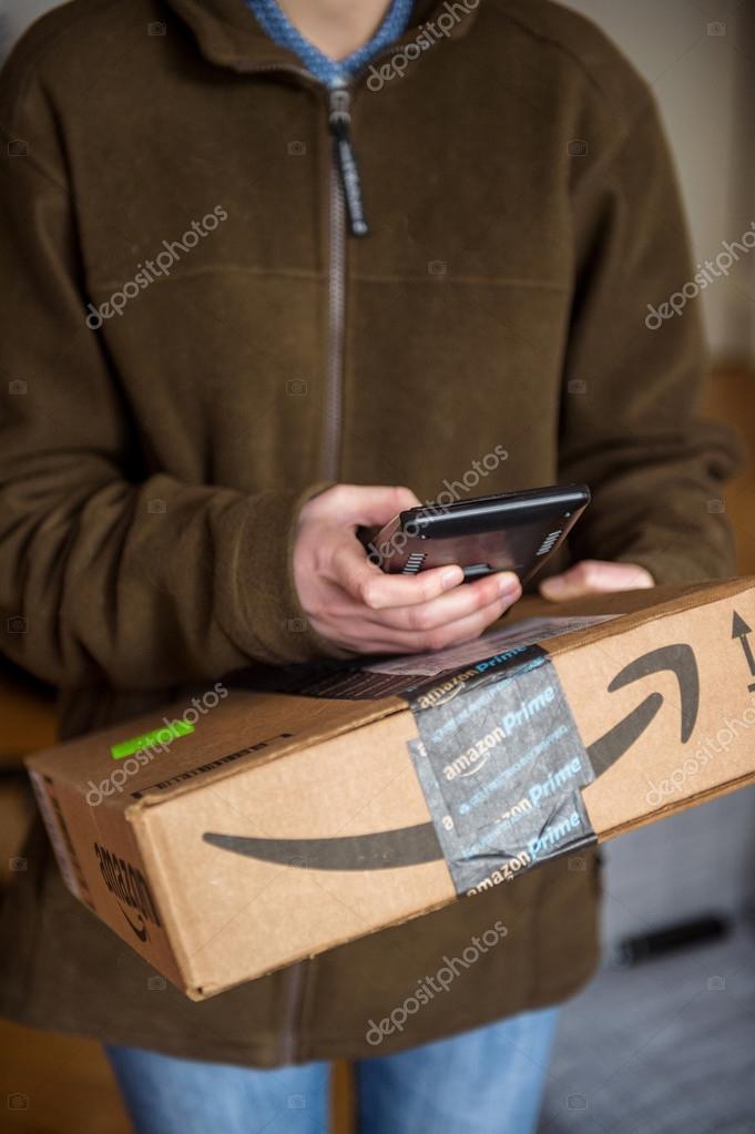 PARIS, FRANCE - JAN 27, 2016: UPS United Parcel Service young female postal delivery courier in front of door scanning the  ontime delivering package from Amazon Prime