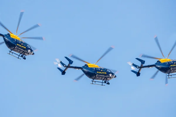 Drie politie helikopter vliegen tegen een heldere blauwe hemel — Stockfoto