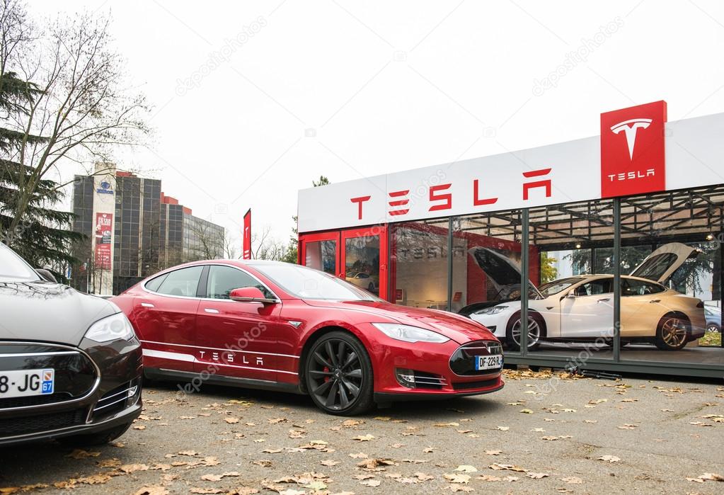 PARIS, FRANCE - NOVEMBER 29: Tesla Model S showroom and two luxury tesla cars outside and one inside. Tesla is an American company that designs, manufactures, and sells electric cars