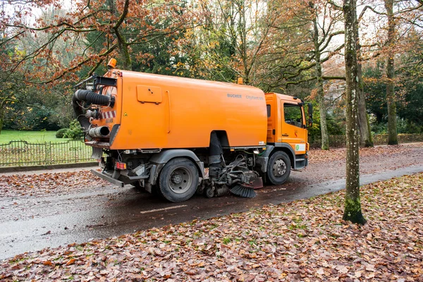 Orangefarbene Straßenkehrmaschine reinigt die Straße — Stockfoto