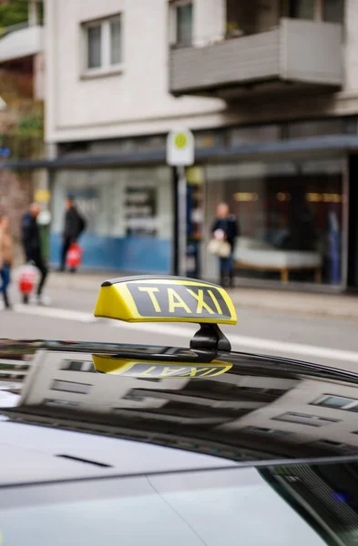 Знак таксі чекає клієнтів у місті з дефокусованою п'єдесталією — стокове фото