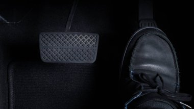 Hızlandırıcı ve fren pedalını sağ ayak, siyah deri ayakkabı ve siyah kot pantolonla iten adamın görüntülerini kapatın. Japon arabasının içinde kamera görüntüsü..