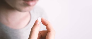 Beyaz ilaç hapı alan ya da elinde tutan insanlar salgın virüslerden korur ve onları sağlıksız ve hastalıklardan korur. Stüdyo yakın çekim ve temiz arkaplan.