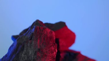 Kara Kömür. Doğal ahşap ya da mavi arka planda geleneksel kömür hareket döngüsü. Statik kamerayla çekilmiş. Mavi ve kırmızı LED ışıklandırmalı 4K. Mangalda mangal kömürü. yiyecek konsepti.