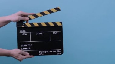 Film alkışlama tahtası. Film ekibi, çekim tahtasını çerçeveye taşıyıp alkışlar ve çerçevenin dışına taşır. Sarı ve siyah şeritli klaket mavi arkaplan prodüksiyonu