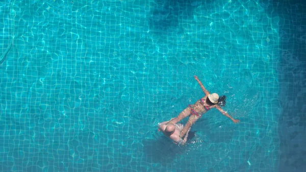 人々はプールで泳いでいる 夏の晴れた日のスイミングプールでは青い色の澄んだ水と人々は楽しみとトップビューの角度 ホテルのプールで夏の暑い日にリラックスしている人と鳥の目の角度 — ストック写真