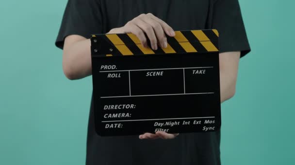 映画クラッパーボード フィルムクルーの男性の手を保持し フレーム内の空の黒と黄色のストライプフィルムスレートを拍手 1アクション 緑の青の背景に黄色と黒の色のクラッパーボード ビデオ制作 — ストック動画