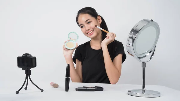 Beauty Blogger. Asian teen woman sit in front of camera and live broadcasting as a beauty blogger influencer or youtuber to review or advice about how to make up at home. studio shot white background.