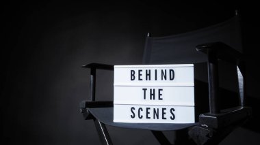 Behind the scenes letterboard text on Lightbox or Cinema Light box. Movie clapperboard and director chair. Background black color. camera shootin in video production studio. clipart