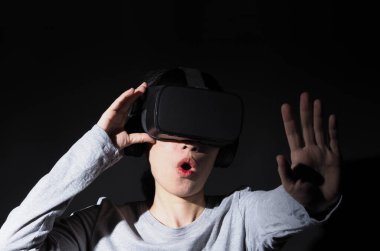 VR kulaklık takan elleri havada bir kız. Sanal gerçeklik gözlüklü Asyalı kadın. Fütürist kavramı. Dijital VR gözlükleri. Modern siyah VR kullanan kadın siber deneyim kazanıyor.
