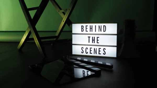 Behind the scenes letterboard text on Lightbox or Cinema Light box. Movie clapperboard megaphone and director chair beside. Background LED color change. static camera in video production studio.