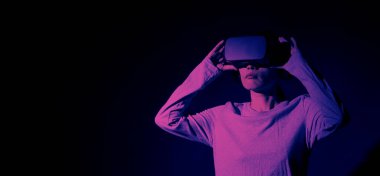 VR kulaklık takan elleri havada bir kız. Sanal gerçeklik gözlüklü Asyalı kadın. Fütürist kavramı. Dijital VR gözlükleri. Modern siyah VR kullanan kadın siber deneyim kazanıyor.