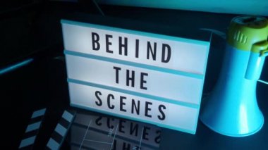 Arka planda, Lightbox 'ın arka plan ışığını değiştiren stüdyo renklerinde antetli metni var. Sinema lşığı kutusu, film tahtası megafonu ve yönetmen koltuğunun yanında. video yapım film kavramı.