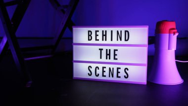 Behind the scenes text on letterboard Lightbox or Cinema Light box. Movie clapperboard or film slate megaphone and director chair beside. Background LED color. shoot in video production studio. clipart