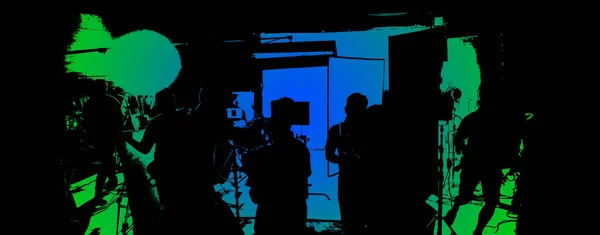 Video production behind the scenes or the making of movie and film crew team working in silhouette of camera and equipment set in studio. Online video shooting process. film industry concept.