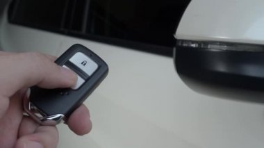 Araba anahtarı uzaktan kumandası. Arabanın uzaktan kumandasının yanındaki kilidi açıp kapatıyorum. Araba anahtarının düğmesine basıyorsun ve kapı açık ya da kapalı olduğunda ışıklar yanıp sönüyor. Uzaktan kumanda kullanan insan eli.