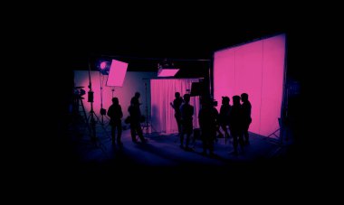 Silhouette images of film production. behind the scenes or b-roll of making video commercial movie. Film crew lightman and cameraman working together with film director in studio. Film industry.