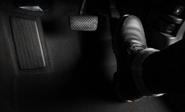 Close up the foot pressing foot pedal of a car to drive. Accelerator and brake pedal in a car. Driver driving the car by pushing accelerator and break pedals of the car. inside vehicle. control pedal.
