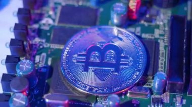 Devre kartında dönen bitcoin. Şifreli bozuk paralar ve bilgisayar anakartları. Dijital para birimi bitcoins BTC ve siber mikro çip. Arka planda pembe mavi renk. Sanal varlık yatırımı.