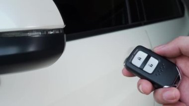 Araba anahtarı uzaktan kumandası. Arabanın uzaktan kumandasının yanındaki kilidi açıp kapatıyorum. Araba anahtarının düğmesine basıyorsun ve kapı açık ya da kapalı olduğunda ışıklar yanıp sönüyor. Uzaktan kumanda kullanan insan eli.