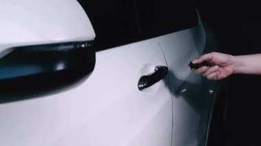 Araba anahtarı uzaktan kumandası. Arabanın uzaktan kumandasının yanındaki kilidi açıp kapatıyorum. Araba anahtarının düğmesine basıyorsun ve kapı açık ya da kapalı olduğunda ışıklar yanıp sönüyor. Uzaktan kumanda kullanan insan eli.