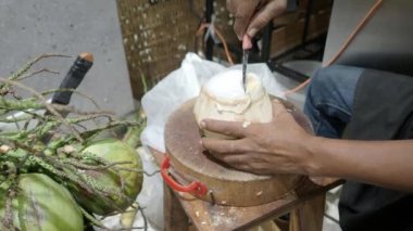 Geleneksel bir şekilde Tayland hindistan cevizi kabuğu soymak. İçinde hindistan cevizi ve su tutuyor. Elle soyulmuş genç hindistan cevizi. Tayland usulü hindistan cevizi soyma. Asya 'nın ünlü yiyecek ve içeceği