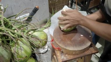 Geleneksel bir şekilde Tayland hindistan cevizi kabuğu soymak. İçinde hindistan cevizi ve su tutuyor. Elle soyulmuş genç hindistan cevizi. Tayland usulü hindistan cevizi soyma. Asya 'nın ünlü yiyecek ve içeceği