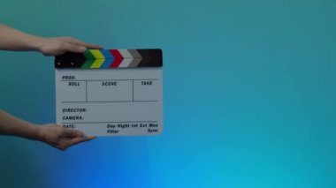 Film alkışlama tahtası. Erkek el ele tutuşur ve film kaydını çerçeveye geçirir, alkışlar ve çerçevenin dışına taşır. Siyah ve beyaz film klip tahtası. Renkli bir geçmiş. Video üretimi. 