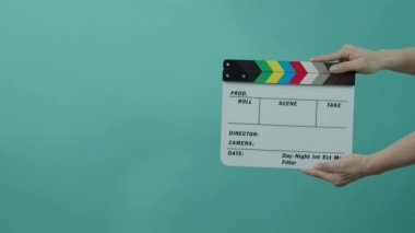 Film alkışlama tahtası. Erkek el ele tutuşur ve film kaydını çerçeveye geçirir, alkışlar ve çerçevenin dışına taşır. Siyah ve beyaz film klip tahtası. Renkli bir geçmiş. Video üretimi. 