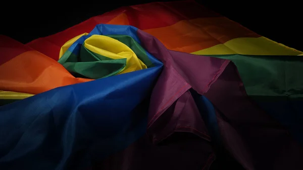 LGBTQ pride flag. Lesbian Gay Bi sexsual Transgender Queer. Homosexsual pride Rainbow flag in gay hand. black background. Represent symbol of freedom, peace, equality and love. LGBTQ concept.