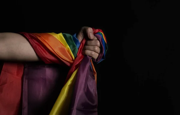 LGBTQ pride flag. Lesbian Gay Bi sexsual Transgender Queer. Homosexsual pride Rainbow flag in gay hand. black background. Represent symbol of freedom, peace, equality and love. LGBTQ concept.