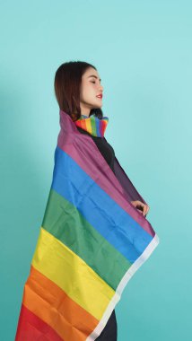 LGBTQ kızı ve gurur bayrağı. Seksi lezbiyen kız ve LGBT bayrağı ayakta duruyor. mavi yeşil arka plan. Boynunda gökkuşağı eşarbı olan Asyalı LGBTQ kadını. Enerjik ve neşeli. LGBTQ kavramı. 