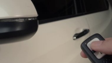Araba anahtarının düğmesine basıyorsun ve kapı açık ya da kapalı olduğunda ışıklar yanıp sönüyor. Araba anahtarı uzaktan kumandası. Arabanın uzaktan kumandasının yanındaki kilidi açıp kapatıyorum. Uzaktan kumanda kullanan insan eli. 