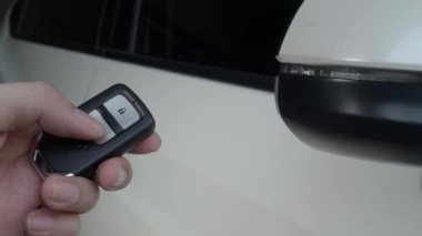 Araba anahtarının düğmesine basıyorsun ve kapı açık ya da kapalı olduğunda ışıklar yanıp sönüyor. Araba anahtarı uzaktan kumandası. Arabanın uzaktan kumandasının yanındaki kilidi açıp kapatıyorum. Uzaktan kumanda kullanan insan eli. 