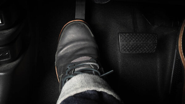 Нога нажимает педаль педали автомобиля для вождения. Ускоритель и тормозная педаль в машине. Водитель за рулем автомобиля нажимает на акселератор и ломает педали автомобиля. Внутри машины. управляющая педаль. Закрыть.