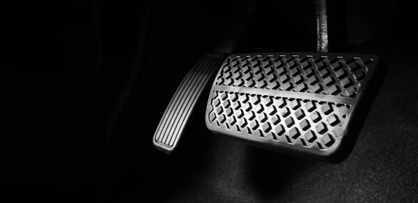 Foot pressing foot pedal of a car to drive. Accelerator and brake pedal in a car. Driver driving the car by pushing accelerator and break pedals of the car. inside vehicle. control pedal. Close up.