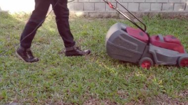 Elektrikli çim biçme makinesi. Çim biçme makineli bir adam. Statik çekim. Bahçe işleri. Bahçede elektrikli çim biçme makinesiyle çim biçmek. Çim biçme makinesi. Çimleri biçiyorum.. 