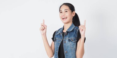 Beyaz arka planda duran Asyalı genç kadın hareketi. Neşeli ve kendinden emin. Mini kalp gibi mimimikler gösteriyor Tamam başparmak yukarı ya da işaret. Mutlu, heyecanlı ve şaşırmış ceket kotları.