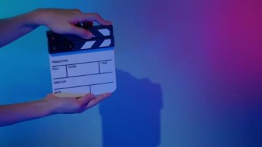 Film Slate or Movie Clapperboard with Blue Green screen background. Film crew man hold and hit film slate in the frame. Clapping film slate. Video production chroma key background. Film production. 