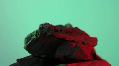 Kömür kömürü. Doğal ahşap ya da geleneksel siyah kömür döngüsü. Renkli LED ışığı olan mavi ya da yeşil ekran arkaplanı. Parazitle çekilmiş. Barbekü ızgarası için kömür. Siyah kömür.