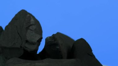 Kömür kömürü. Doğal ahşap ya da geleneksel siyah kömür döngüsü. Renkli LED ışığı olan mavi ya da yeşil ekran arkaplanı. Parazitle çekilmiş. Barbekü ızgarası için kömür. Siyah kömür.