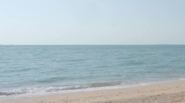 Pattaya Sahili. Tatil yatakları ve kumsalda şemsiyeli kahve masası. Deniz mavi gökyüzü ile el sallıyor. Pattaya Tayland sahillerinde hafif rüzgar. Covid 19 ya da Coronavirus salgını sırasında kimse yok..