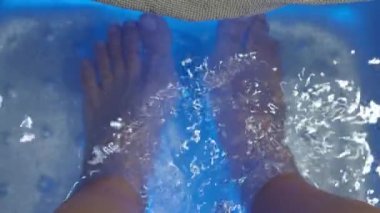 Ayak Spa 'sı. Kaplıcadaki sabun su makinesinde çıplak ayakla masaj yapan bir kadın. Sıcak suda ayak banyosuna giren kadınların ayakları. Kaplıca salonundaki yağ ile ayak masajı. Cilt bakımı.