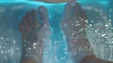 Ayak Spa 'sı. Kaplıcadaki sabun su makinesinde çıplak ayakla masaj yapan bir kadın. Sıcak suda ayak banyosuna giren kadınların ayakları. Kaplıca salonundaki yağ ile ayak masajı. Cilt bakımı.