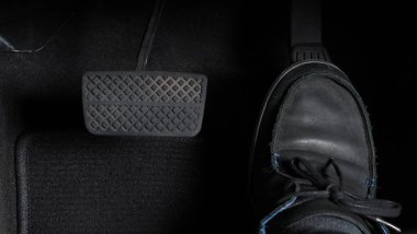 Adam ayağı, gaz pedalı ve arabanın içinde fren pedalı ve hangi siyah deri ayakkabının üzerine bastığını kopyala. Otomobil hızını artırmak veya kontrol etmek için. Otomobil Sürücüsü kavramı